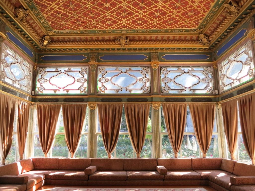 The ornate, gilded interior of the Sofa Pavilion, showcasing the masterful woodwork and large windows designed for garden views.