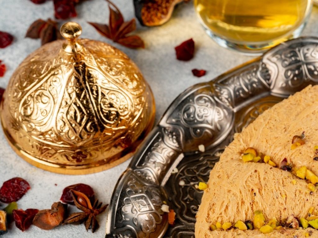 An exquisite presentation of traditional Ottoman desserts, featuring decadent pistachio helva on an ornate silver platter, embodying the rich culinary heritage of the imperial palace.