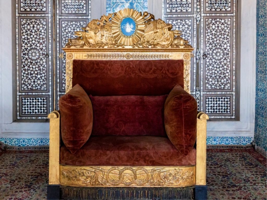 The magnificent gilded throne of Sultan Ahmed I, a priceless artifact from the Imperial Treasury, set against a backdrop of intricate mother-of-pearl inlay and brilliant Iznik tiles.