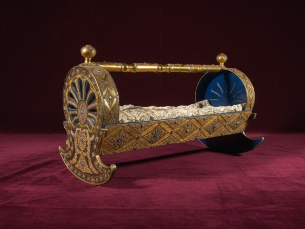 The exquisite golden cradle from the Imperial Treasury, a lavish gift for a newborn prince, adorned with intricate enamel work, diamonds, and precious gems.